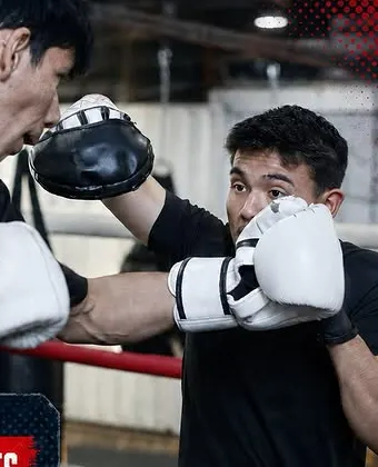 Dos alumnos de boxeo intercambiando golpes con guantes blancos