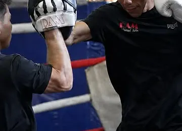 Alumnos entrenando kickboxing con pads y guantes sobre un ring